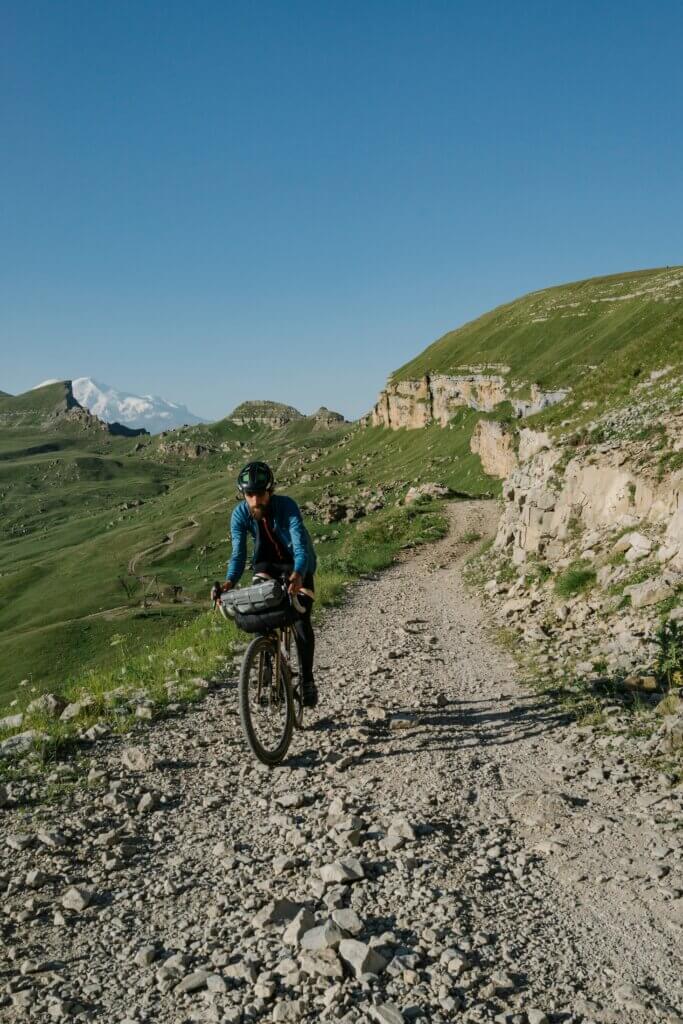 Turni kolesar na MTB kolesu, z gorami v ozadju.